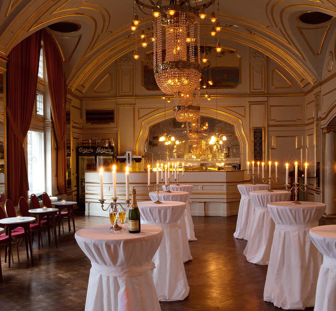 Bild på Oscarsteaterns guldfoaje med kandelaber på varje bord med tända ljus